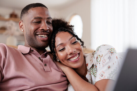 Happy couple relaxing together while using laptop at home