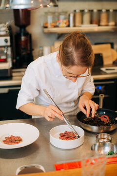 Chef plating gourmet meat dish in restaurant kitchen