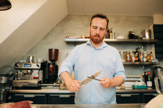 Man sharpening knife in professional kitchen