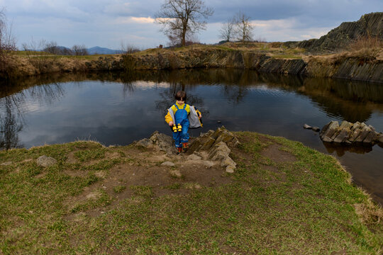 Child exploring rocky lakeshore with binoculars