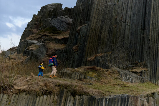 Hiker on basalt columns rock formation by lake