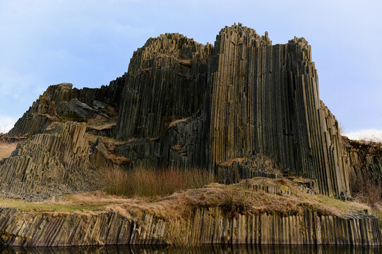 Basalt rock formations reflected in calm water
