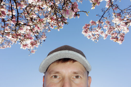 A man takes a selfie against the backdrop of the sky and magnolia