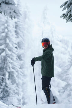 A skier standing in a snow-covered forest at a ski resort