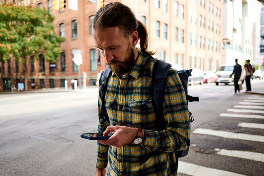 Man stares at his phone while crossing the street in Brooklyn