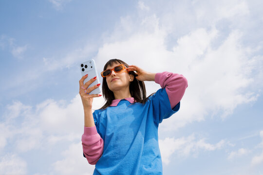 Young woman enjoys sunny spring day while using her phone outdoors