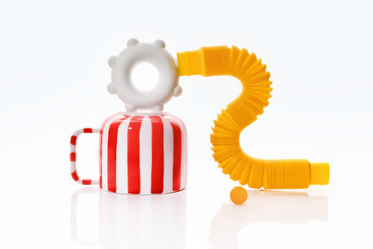 Playful abstract still life with striped cup and flexible yellow tube