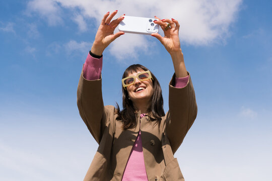 Woman takes selfie in blue sky during spring day with vibrant colors