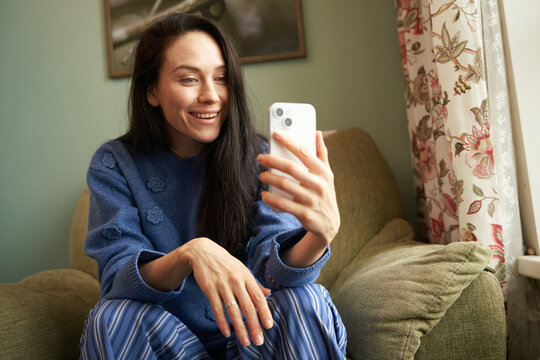Woman making video call on smartphone at home