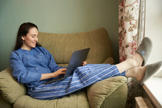 Woman working on laptop in cozy armchair