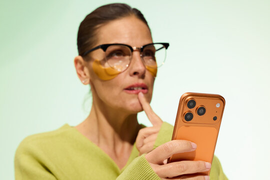 Woman Using Smartphone While Thinking in Studio Setting