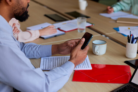 Anonymous man holds his phone on a meeting