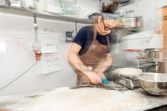 Baker preparing fresh bread dough in bakery kitchen
