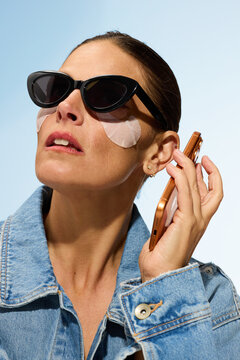 Woman Talks on Phone While Wearing Sunglasses in a Bright Setting