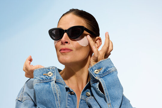 Woman Applying Skincare Product Outdoors in Sunny Weather