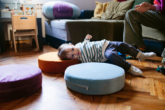 Toddler Playing On Cushions In Living Room