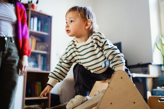 Toddler Climbing Wooden Toy At Home With Parent