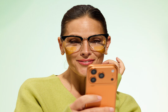 Woman Uses Smartphone While Smiling in Bright Light Setting