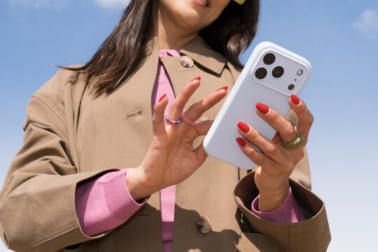 Young person using smartphone outdoors in spring sky