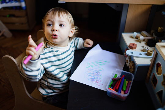 Toddler Drawing With Crayons at Playroom Table