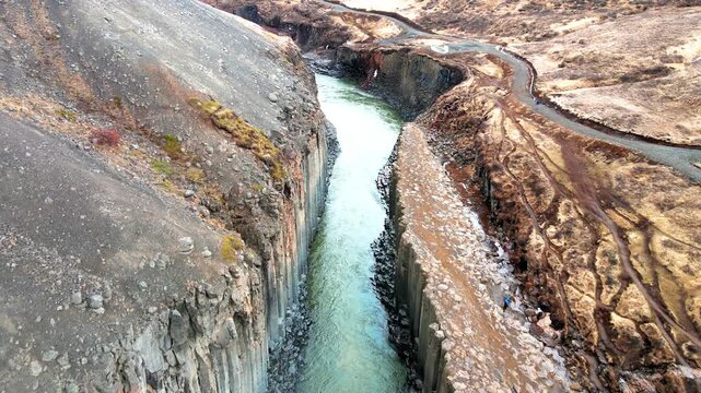 Aerial view of Studlagil Canyon featuring towering basalt columns and the turquoise Jokulsa a Bru river flowing through the gorge Eiriksstadhir, Mulathing, Iceland.