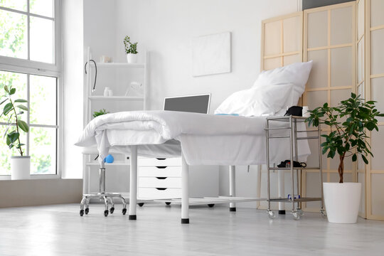 Interior of hospital ward with bed and shelf unit