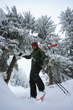 Low angle skier  standing in a snow-covered forest at a ski resort