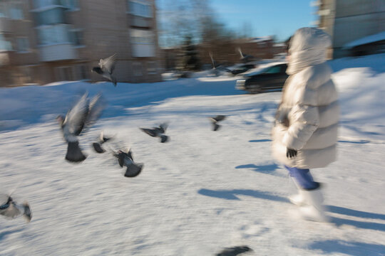 Person Walking in Snow While Birds Fly Around in Winter Scene