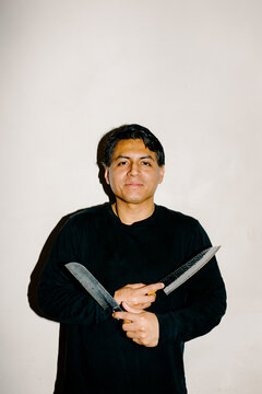 Portrait of chef posing with knives and looking confidently at camera