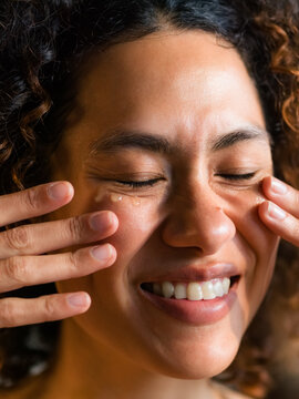 Smiling woman smearing face serum 
