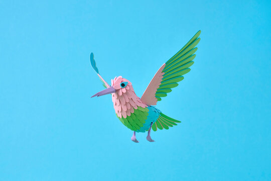 Paper hummingbird flying on bright blue