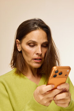 Woman Checking Smartphone With Orange Case in Indoor Setting