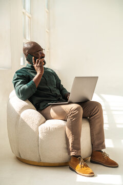 Black businessman Talking on Phone And Working in Minimalistic Studio