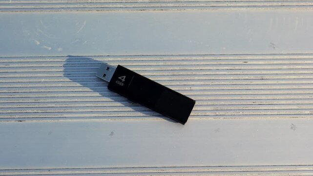 Unsuspecting man finds lost USB thumb drive on ground illustrating malicious USB drop attack - Cybersecurity Information Technology Concept