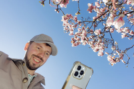 A man takes a selfie against the backdrop of the sky and magnolia