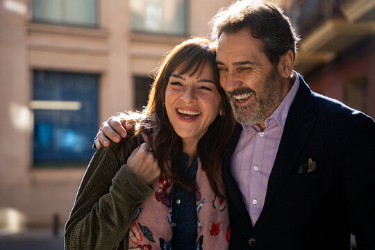 Happy middle-aged couple laughing and embracing outdoors