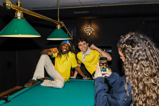 Friends posing for smartphone at pool table