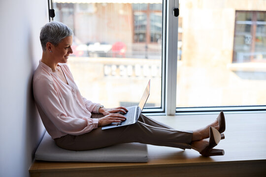 Businesswoman works on a laptop by the window