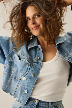 Woman Smiles While Posing in Denim Jacket With Heart Design