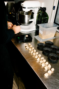 Unknown chef dividing and weighing dough balls on a steel counter