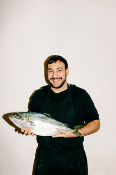 Professional chef smiling and holding a fresh fish