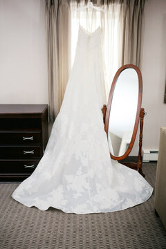 wedding dress on hanger on window of bridal suite