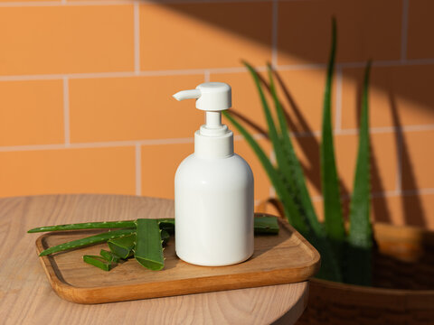 White pump bottle with fresh aloe vera leaves on a wooden tray