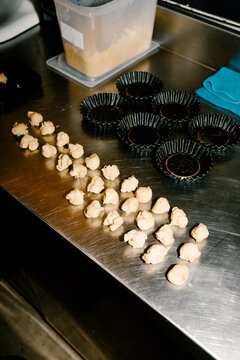 Pieces of pastry lined up on stainless steel next to curly metal molds