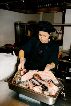 A chef weighing fresh fish on a scale
