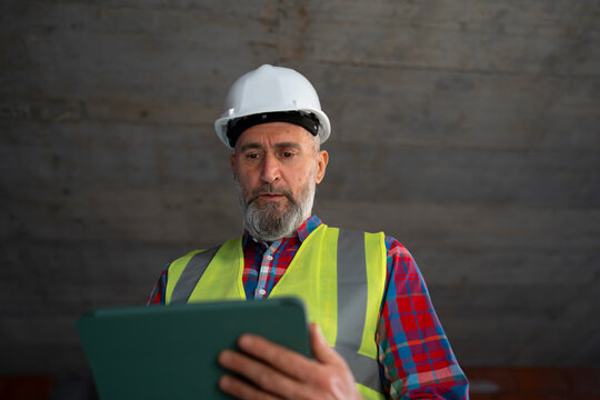 Worker checks data on tablet in safety gear