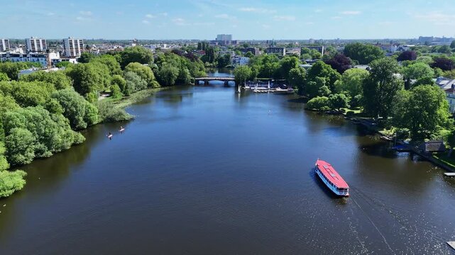 Aerial view of the Aussenalster lake with a red boat cruising on the water surrounded by lush green trees in Hamburg, Hamburg, Germany.