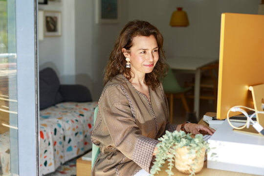 Woman Working at a Desk With a Computer in a Home Office