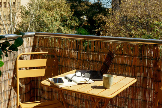 Sunny Balcony Desk Setup with Laptop Notebook and Coffee