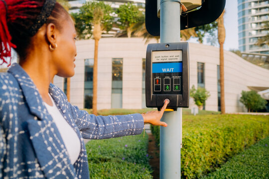 The woman presses the button to call the traffic light